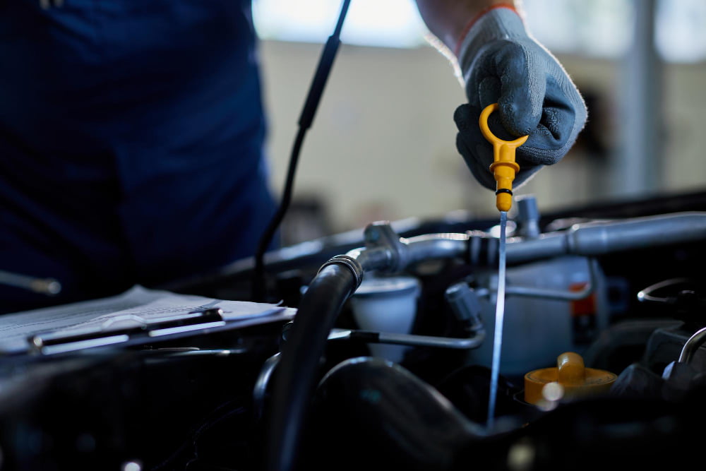 Com que frequência é preciso trocar o óleo do motor? 2 closeup auto repairman checking car oil workshop