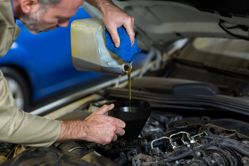 Com que frequência é preciso trocar o óleo do motor? 3 mechanic pouring oil into car engine