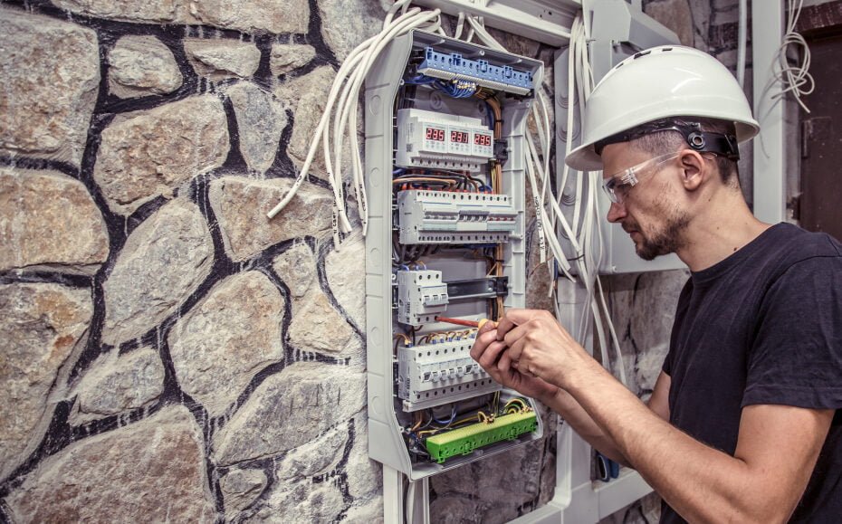 male electrician works switchboard with electrical connecting cab