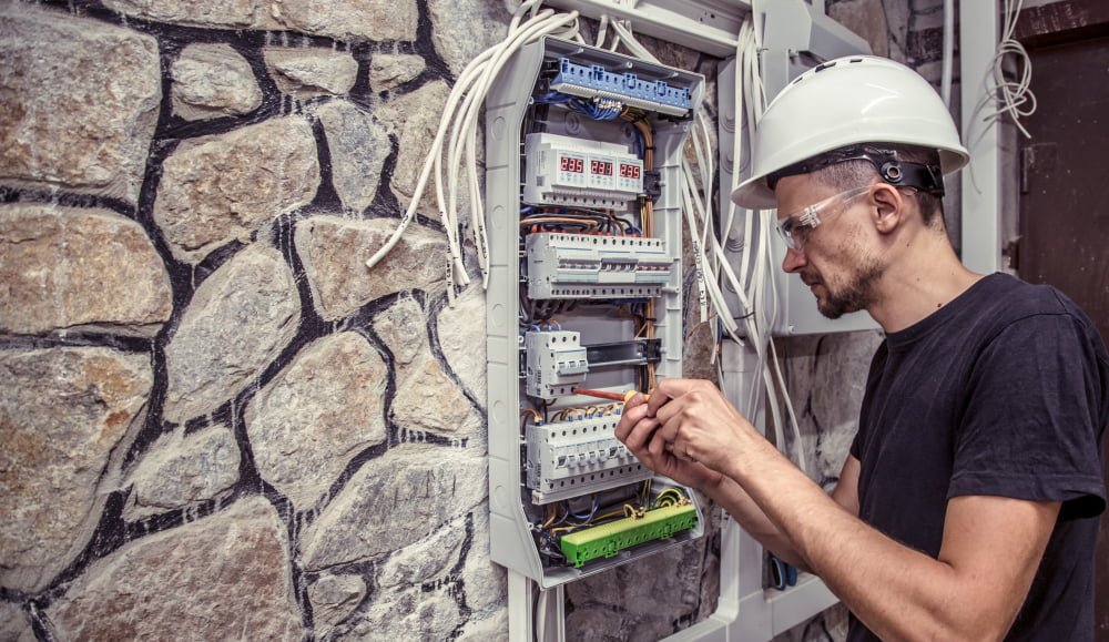 Como solicitar instalação residencial Enel? 3 male electrician works switchboard with electrical connecting cab