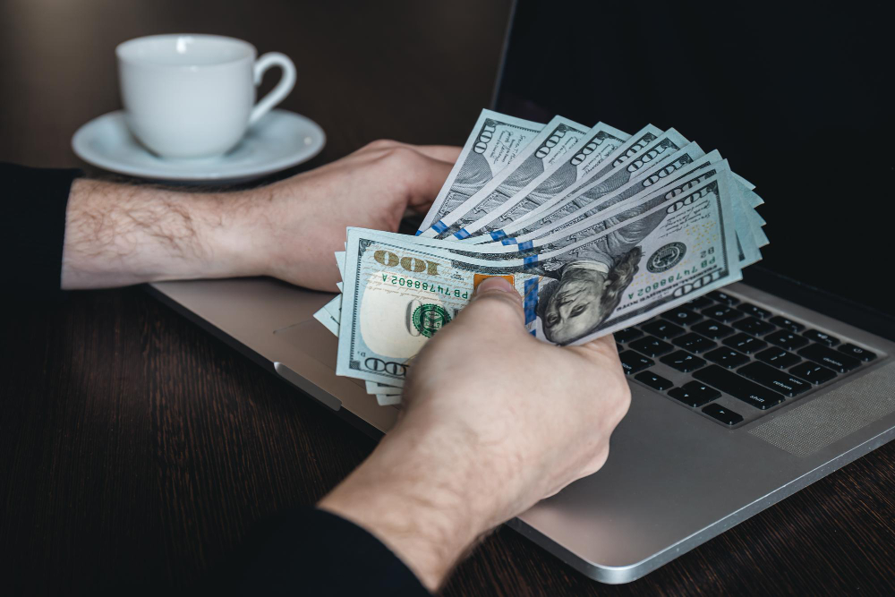 Como trabalhar para ganhar em dólares? 3 notas de dolar fechadas em maos masculinas o conceito de ganhar dinheiro e trabalhar